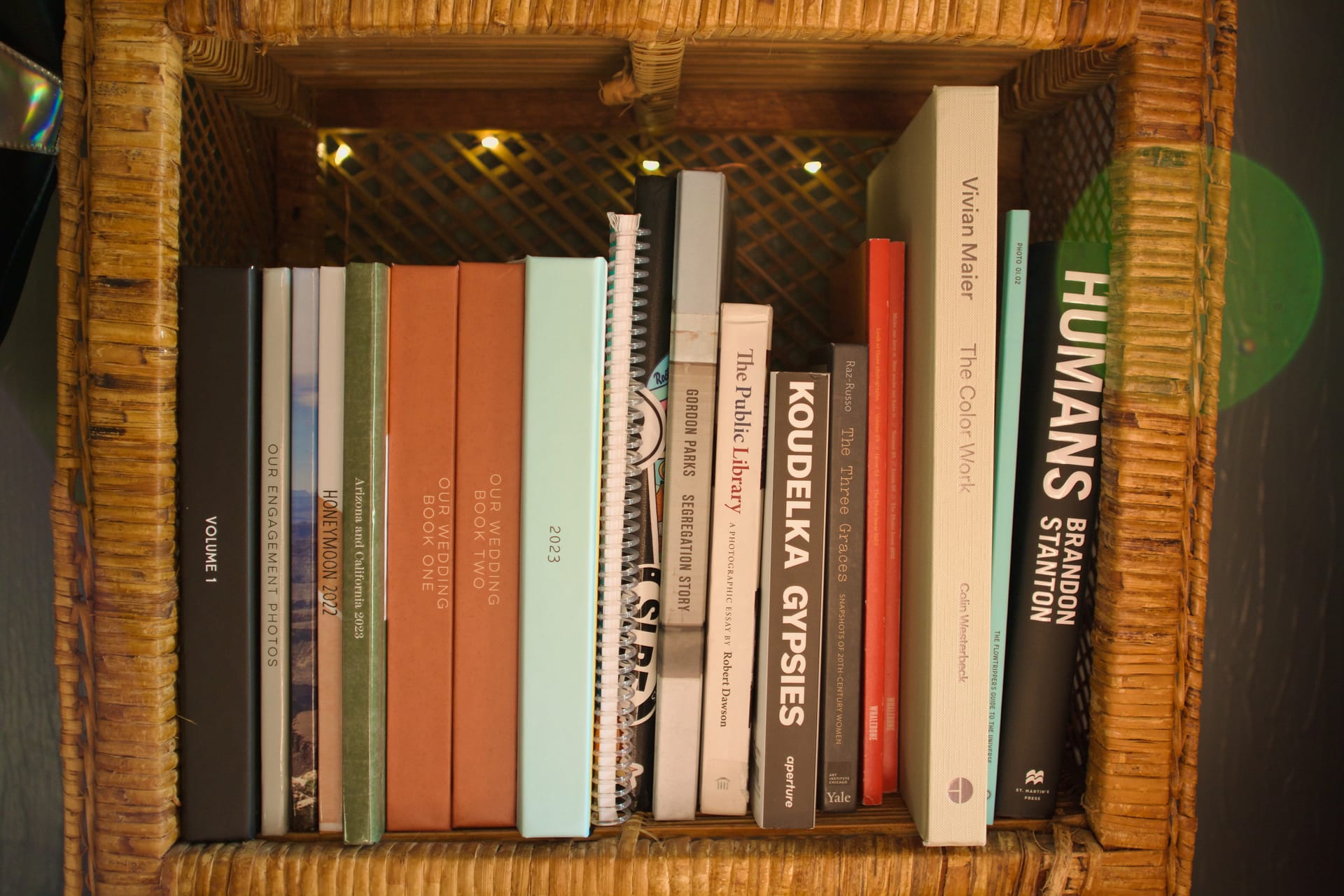 A collection of photo books on a wicker shelf.